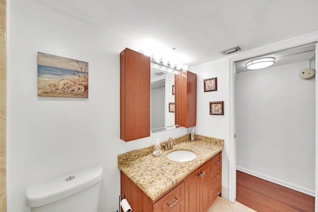 bathroom featuring toilet, vanity, and hardwood / wood-style flooring