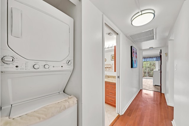 laundry room featuring light hardwood / wood-style floors and stacked washer / drying machine