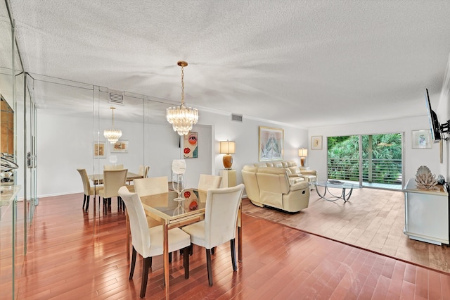 dining room with a textured ceiling, hardwood / wood-style flooring, and an inviting chandelier