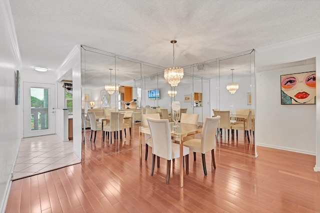 dining area featuring crown molding, a textured ceiling, and light hardwood / wood-style flooring