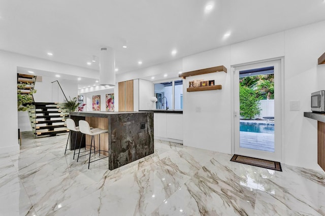 kitchen with a breakfast bar area, sink, and white cabinets