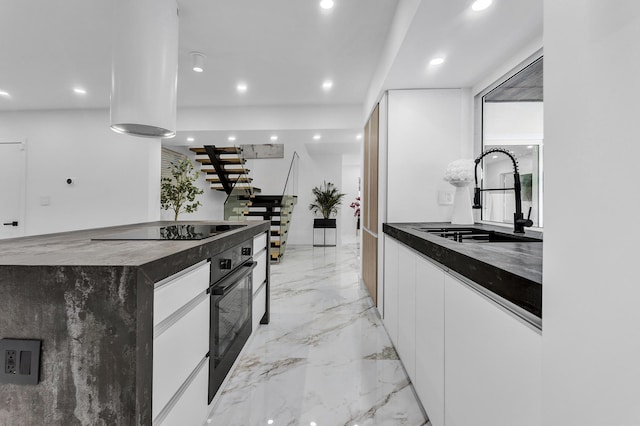 kitchen featuring sink, a center island, white cabinetry, and black appliances