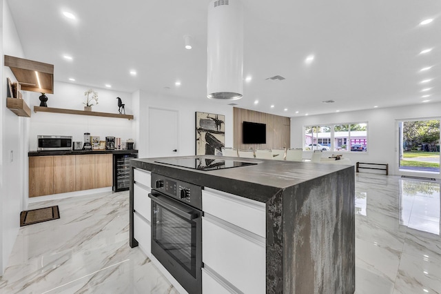 kitchen featuring black appliances, a center island, white cabinets, and wine cooler