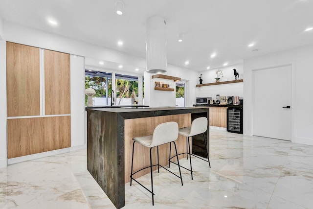 kitchen with a breakfast bar area, a center island, and beverage cooler