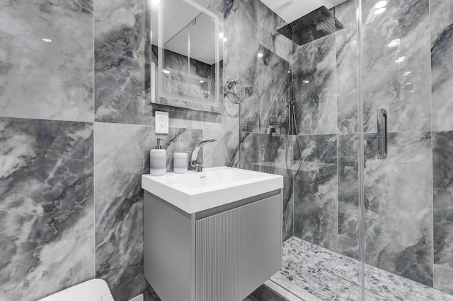 bathroom featuring walk in shower, vanity, toilet, and tile walls