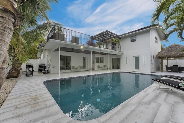 back of property with a fenced in pool, ceiling fan, a balcony, and a patio