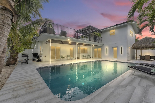 pool at dusk featuring a patio area and ceiling fan