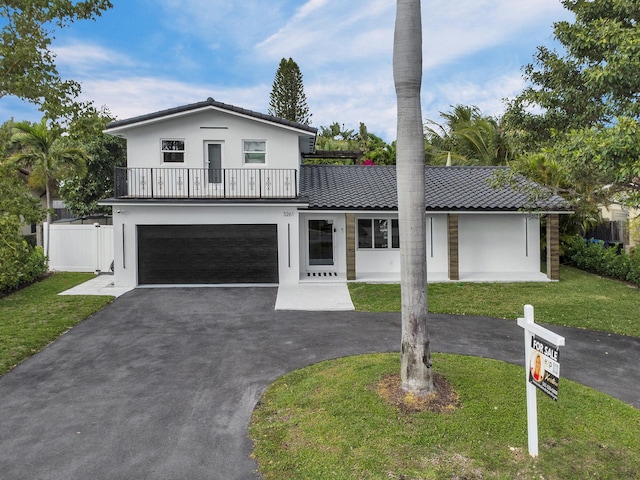 view of front of house with a balcony, a front lawn, and a garage