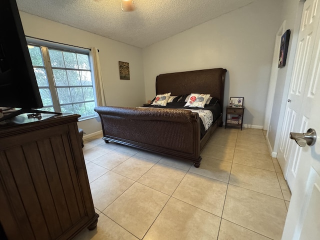 tiled bedroom with ceiling fan, a closet, and a textured ceiling