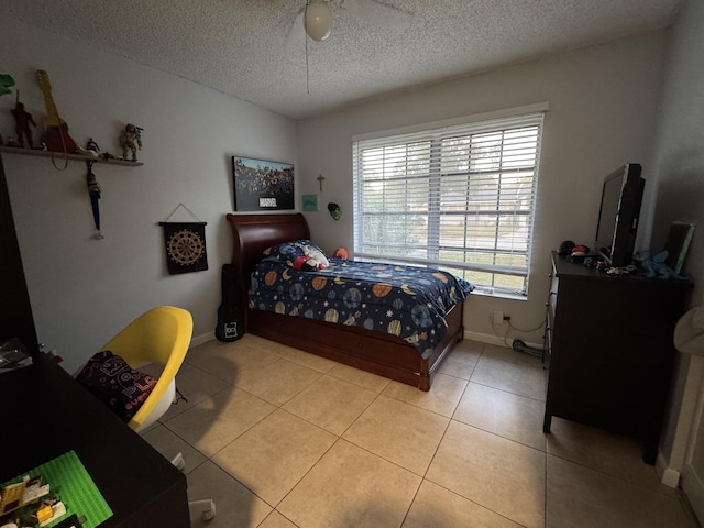 bedroom with ceiling fan, light tile patterned floors, and a textured ceiling