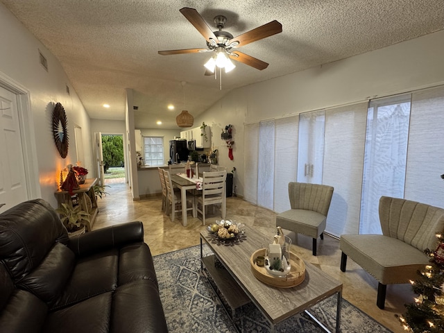 living room featuring ceiling fan, light tile patterned flooring, and a textured ceiling