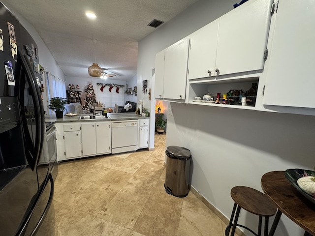 kitchen with ceiling fan, dishwasher, sink, black fridge, and white cabinets