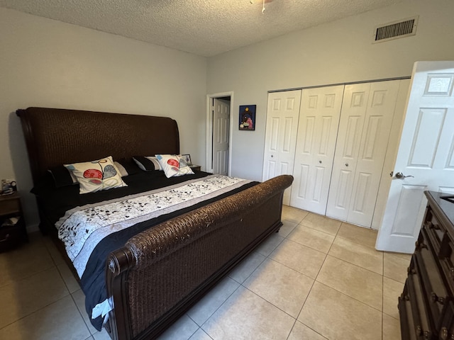 bedroom with light tile patterned floors, a textured ceiling, and a closet