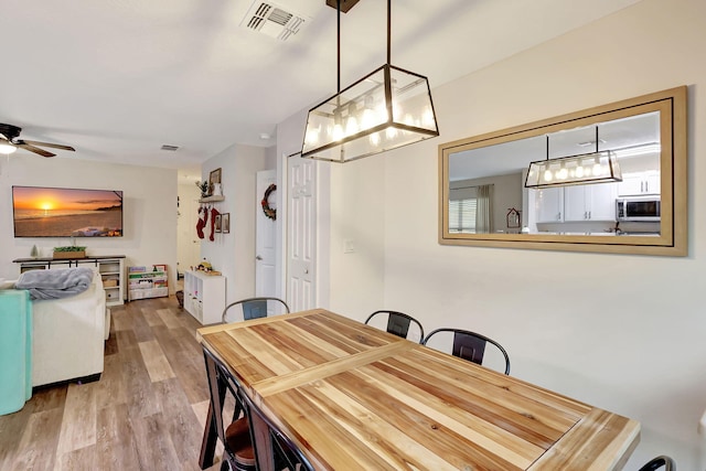 dining room with ceiling fan and light hardwood / wood-style flooring