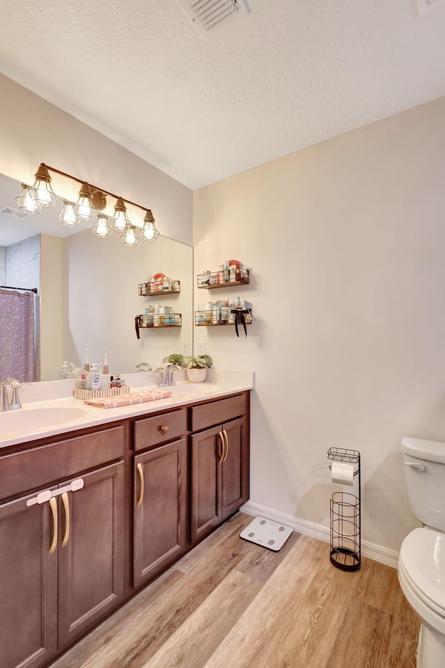 bathroom featuring vanity, hardwood / wood-style flooring, a shower with shower curtain, toilet, and a textured ceiling