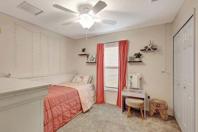 carpeted bedroom with ceiling fan, a textured ceiling, and a closet