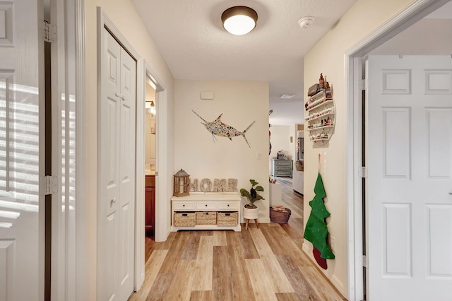 corridor featuring a textured ceiling and light wood-type flooring