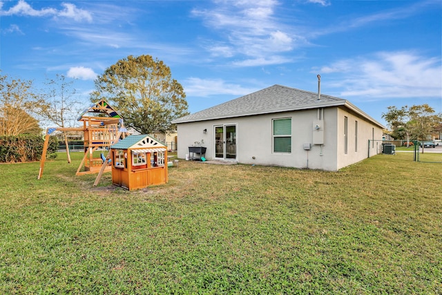 rear view of property featuring a playground, a yard, and central air condition unit