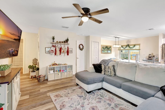 living room featuring ceiling fan, sink, and light hardwood / wood-style flooring