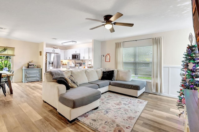 living room featuring ceiling fan, light wood-type flooring, and a wealth of natural light