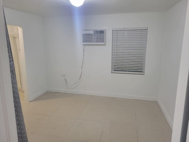 empty room featuring an AC wall unit and light tile patterned flooring