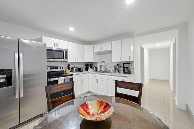 2365 NW 68th St, Miami, FL 33147 - kitchen featuring appliances with stainless steel finishes, a sink, decorative backsplash, white cabinetry, and recessed lighting