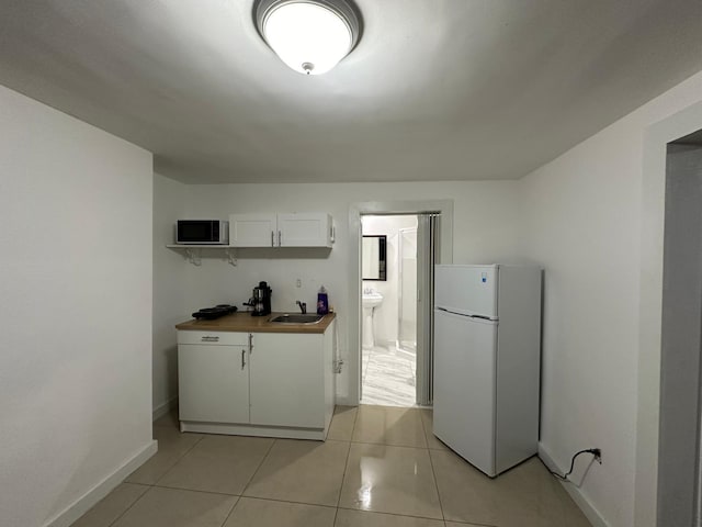 2365 NW 68th St, Miami, FL 33147 - kitchen with freestanding refrigerator, baseboards, white cabinets, a sink, and light tile patterned floors