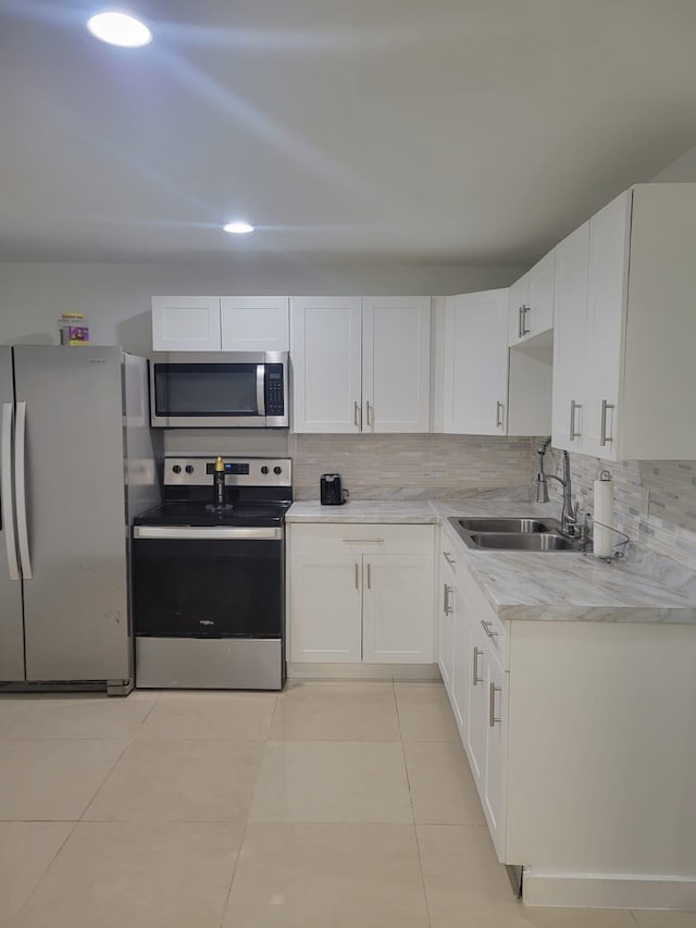 kitchen with white cabinetry, sink, stainless steel appliances, backsplash, and light tile patterned flooring