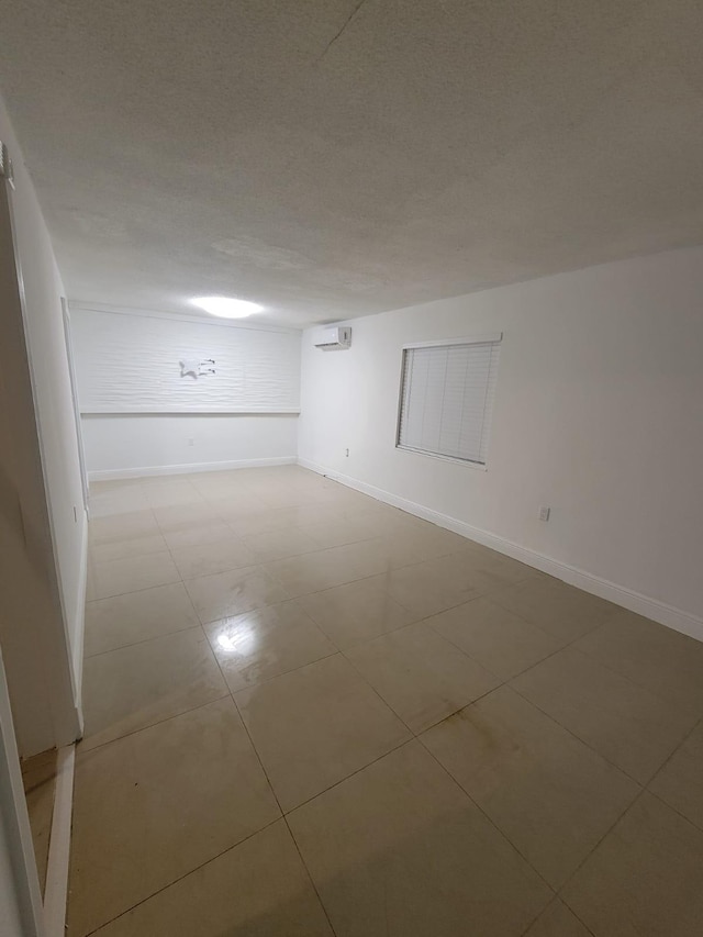 tiled spare room with a wall mounted air conditioner and a textured ceiling