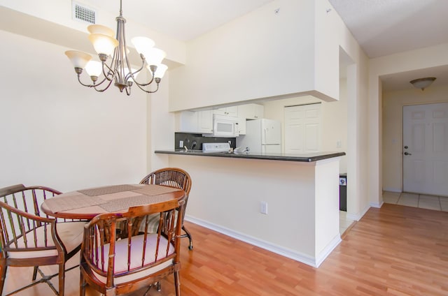 dining space featuring a notable chandelier and light hardwood / wood-style floors