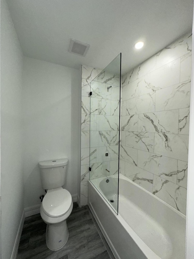 bathroom featuring tiled shower / bath combo, wood-type flooring, and toilet