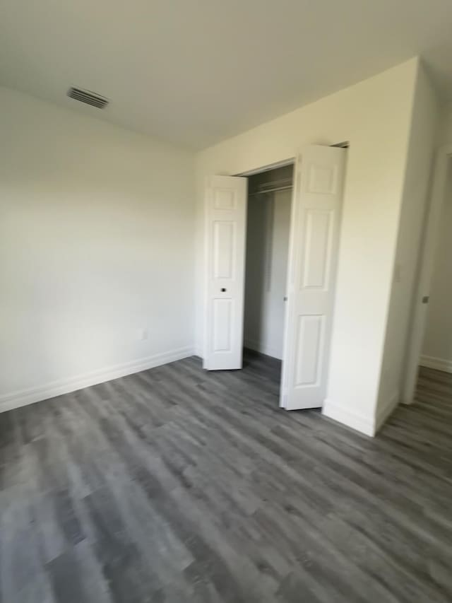 unfurnished bedroom featuring dark hardwood / wood-style floors and a closet