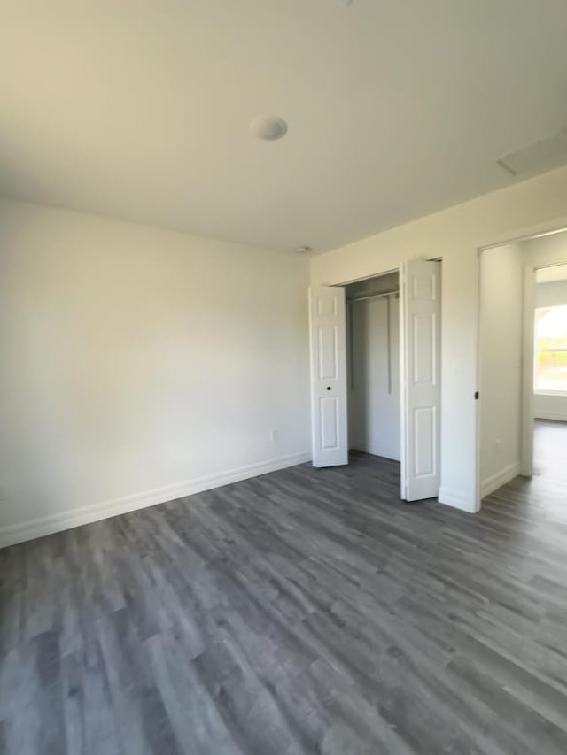 unfurnished bedroom with dark hardwood / wood-style flooring and a closet