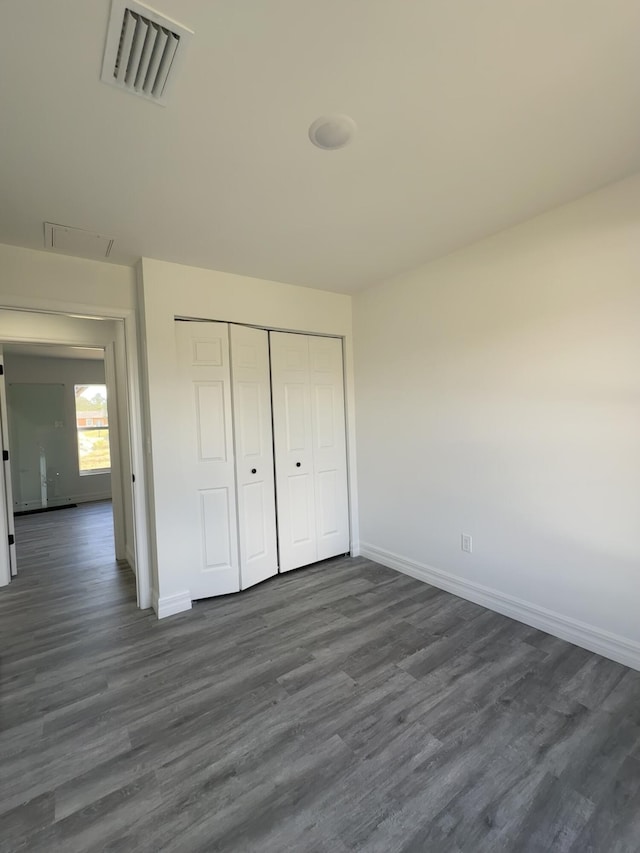 unfurnished bedroom featuring dark wood-type flooring and a closet