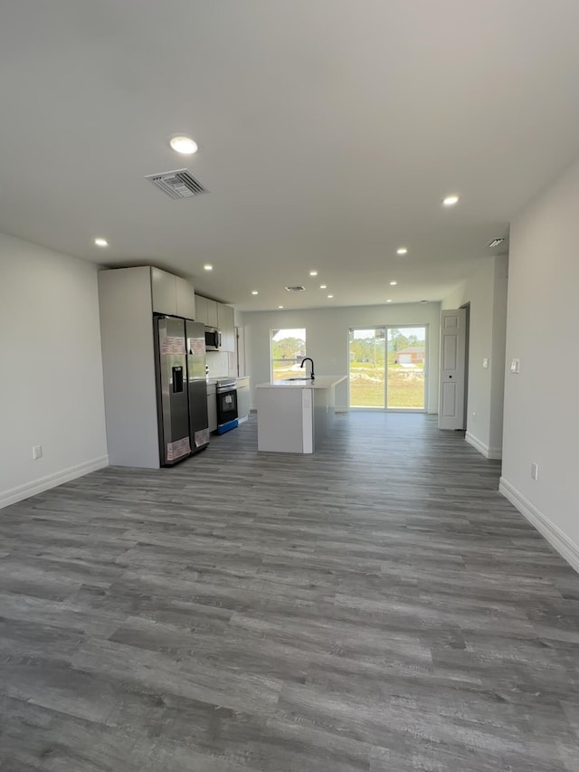 unfurnished living room featuring wood-type flooring and sink