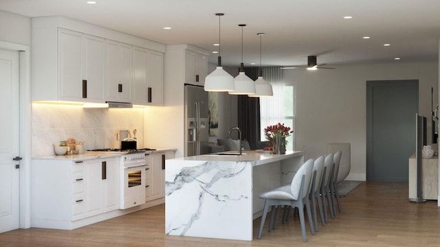 kitchen with a large island with sink, sink, white cabinets, and light hardwood / wood-style flooring