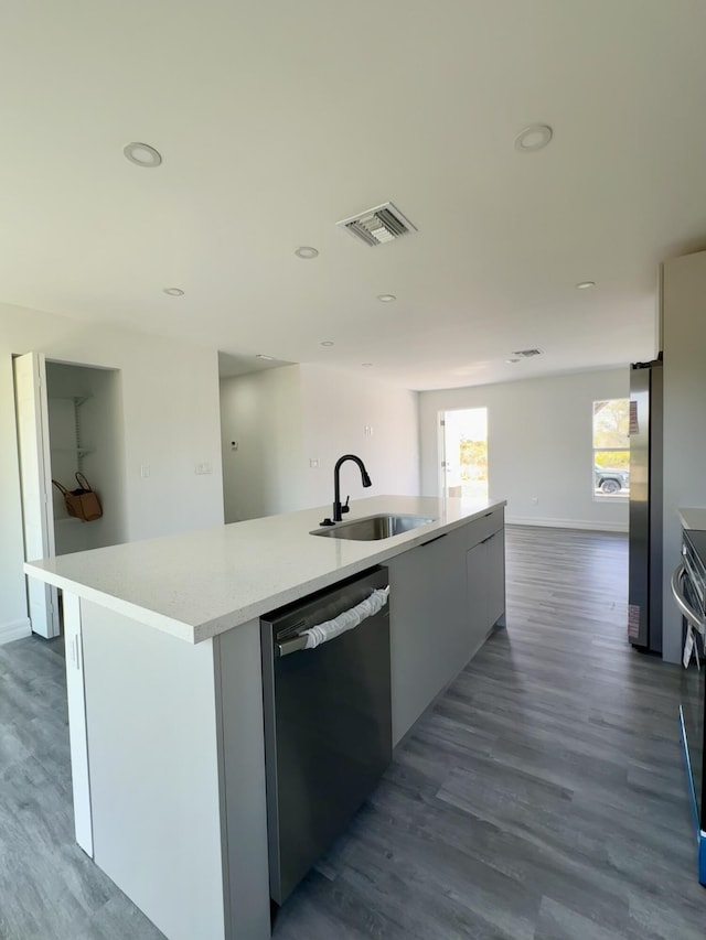 kitchen featuring sink, stainless steel refrigerator, dishwasher, and a center island with sink