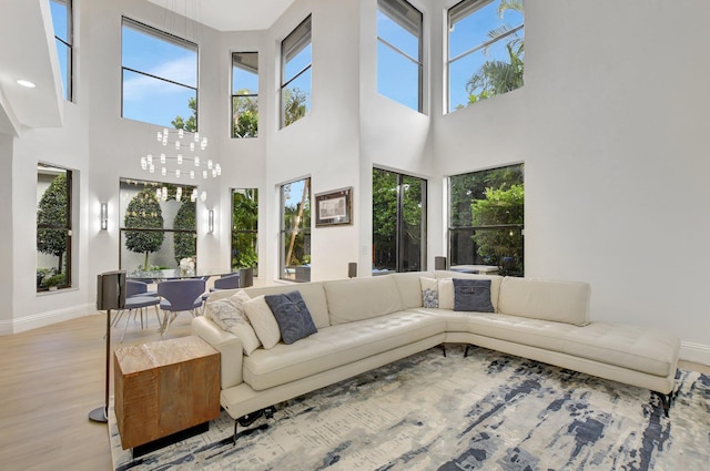 living room with light hardwood / wood-style floors, a high ceiling, and an inviting chandelier