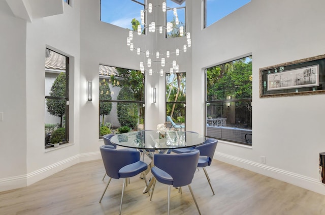 dining room featuring a towering ceiling, light hardwood / wood-style flooring, and plenty of natural light