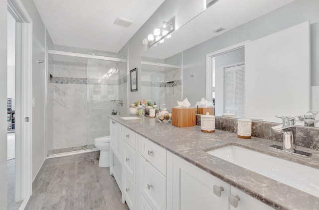 bathroom with a shower with door, vanity, hardwood / wood-style floors, and toilet