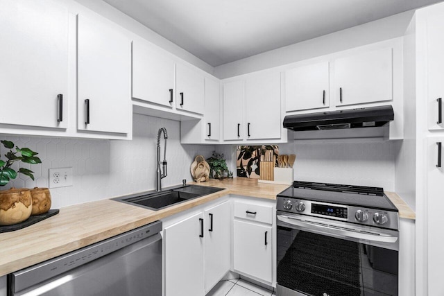 kitchen with sink, stainless steel appliances, light tile patterned floors, decorative backsplash, and white cabinets