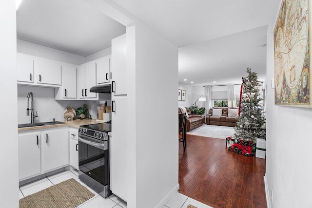 kitchen with white cabinets, electric range, sink, and light tile patterned floors