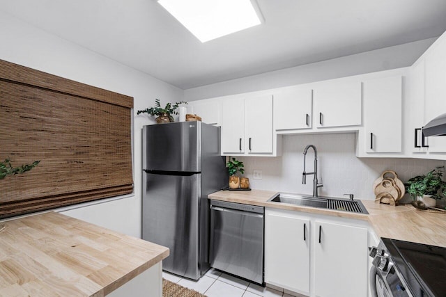 kitchen with white cabinets, appliances with stainless steel finishes, light tile patterned flooring, and sink