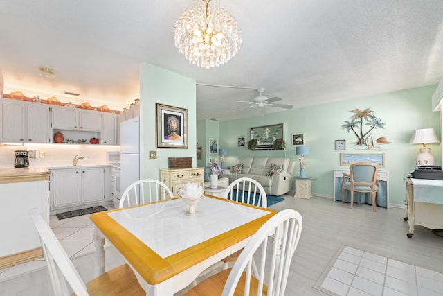 dining area featuring a textured ceiling, ceiling fan with notable chandelier, and sink