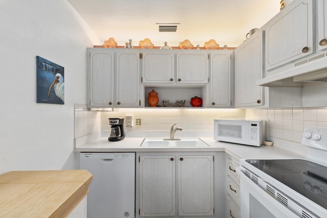 kitchen with decorative backsplash, white appliances, premium range hood, and sink