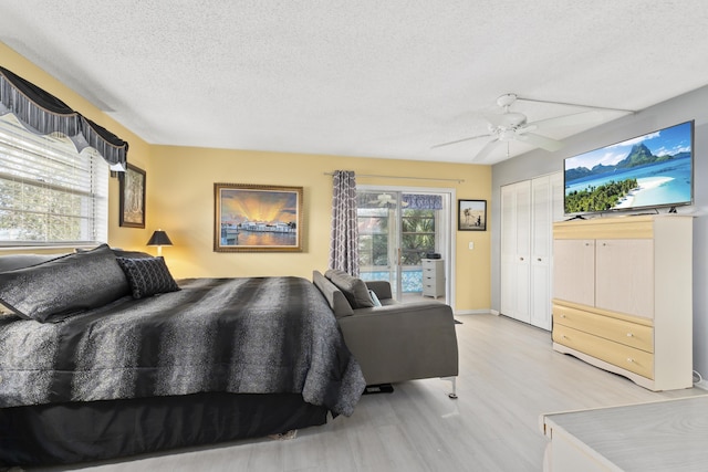 bedroom with multiple windows, ceiling fan, light hardwood / wood-style floors, and a textured ceiling