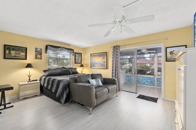 bedroom with ceiling fan, access to exterior, a textured ceiling, and multiple windows