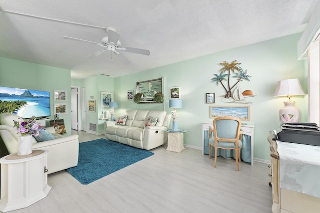 living room with a textured ceiling, light wood-type flooring, and ceiling fan