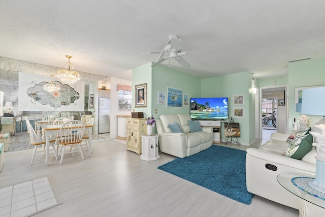 living room with a textured ceiling, hardwood / wood-style floors, and ceiling fan with notable chandelier