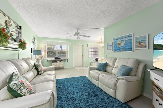 living room featuring light wood-type flooring, a textured ceiling, and ceiling fan